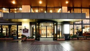 A hotel entrance with a covered walkway, glass doors, and a signboard. - Unzen Sky (UNZEN)