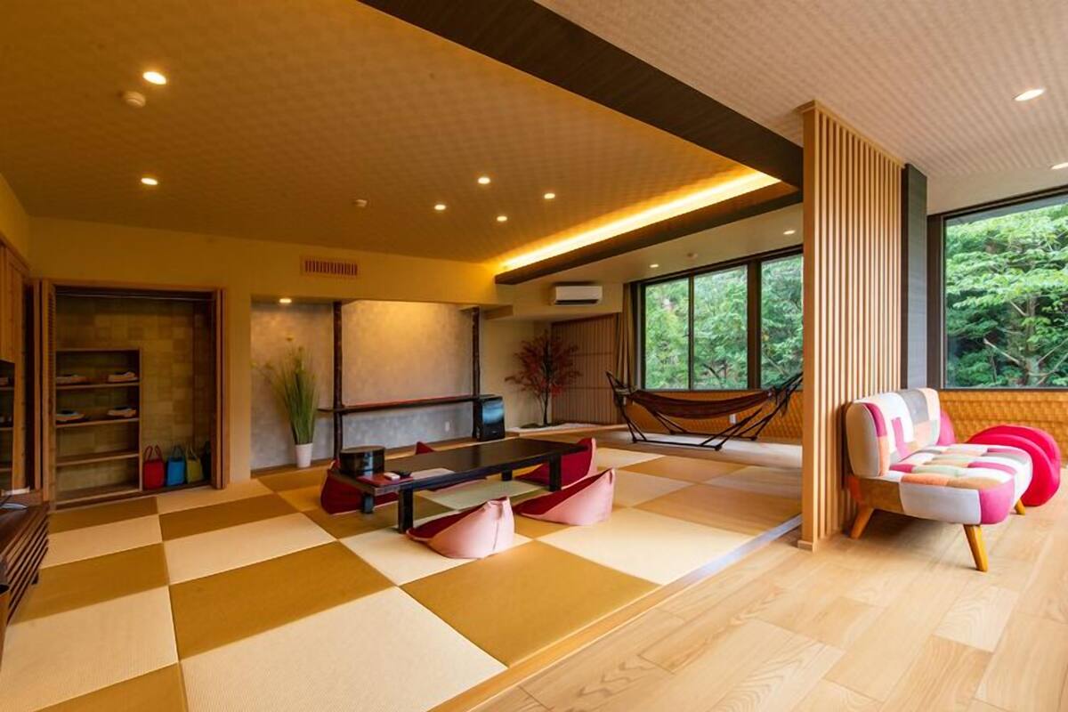A modern living room with tatami flooring, a sofa, a coffee table, and a hammock.