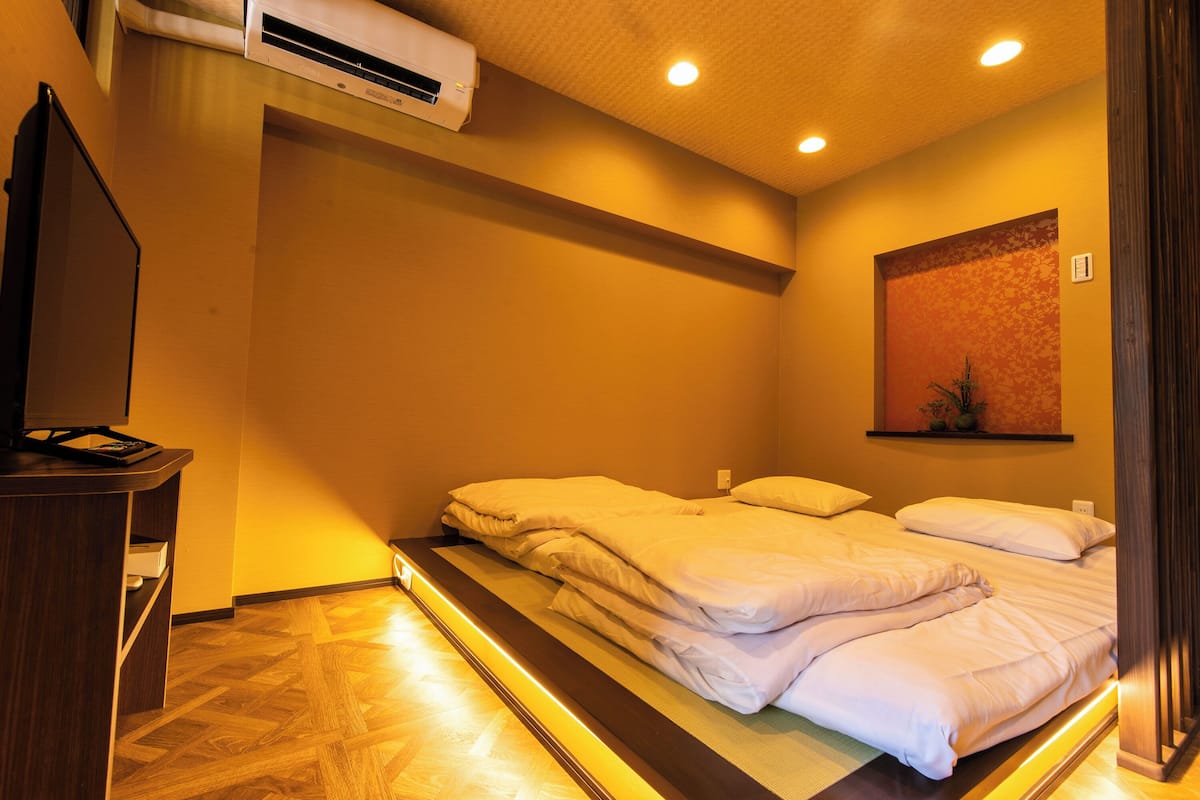 A hotel room with a bed, a desk, and an air conditioning unit.