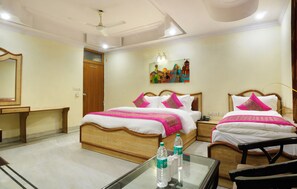 A hotel room with two beds, a desk, a chair, a mirror, and a ceiling fan.