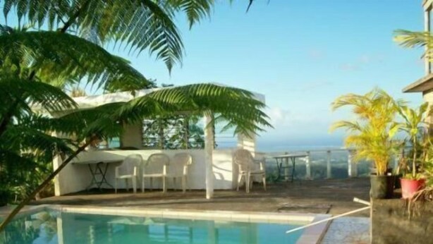 A swimming pool with a clear view of the ocean, surrounded by palm trees and outdoor seating. - Dave Parker's Eco Lodge (Apia)
