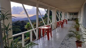 A covered outdoor area with a tiled floor, white railings, and red plastic chairs. - Dave Parker's Eco Lodge (Apia)
