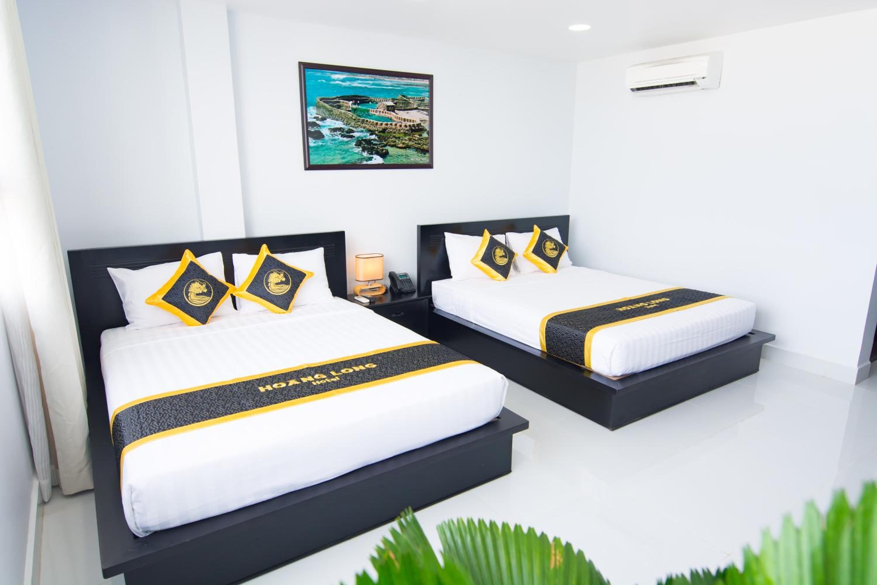 Dos camas con cabeceras y almohadas a juego, un cuadro en la pared y un equipo de aire acondicionado.