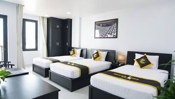 A hotel room with three beds, a desk, and a large window.