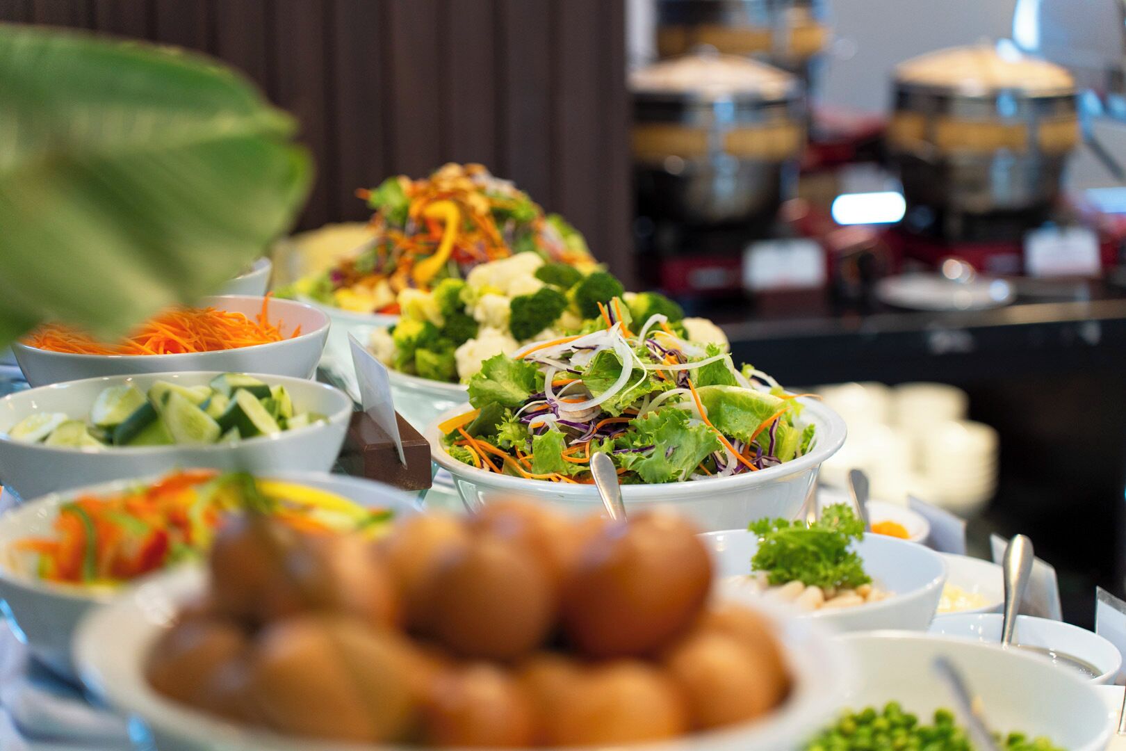 Une table de buffet proposant divers plats, notamment des salades, des légumes et un assortiment de fruits secs.