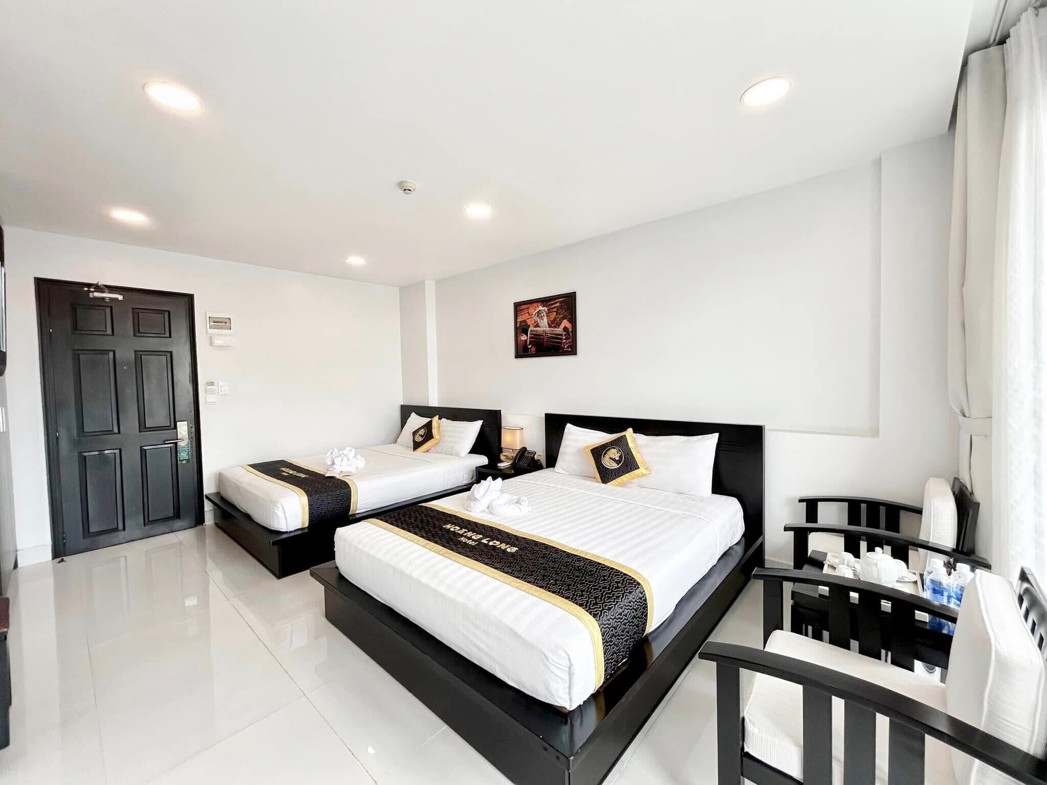 A hotel room with two beds, a desk, and a chair.