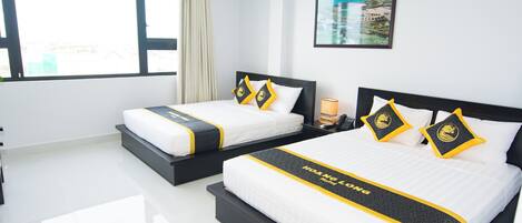 A hotel room with two beds, each with matching headboards and pillows, and a large window providing a view of the city.