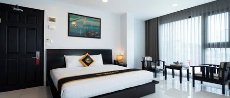 A modern hotel room with a large bed, a desk, and a chair.