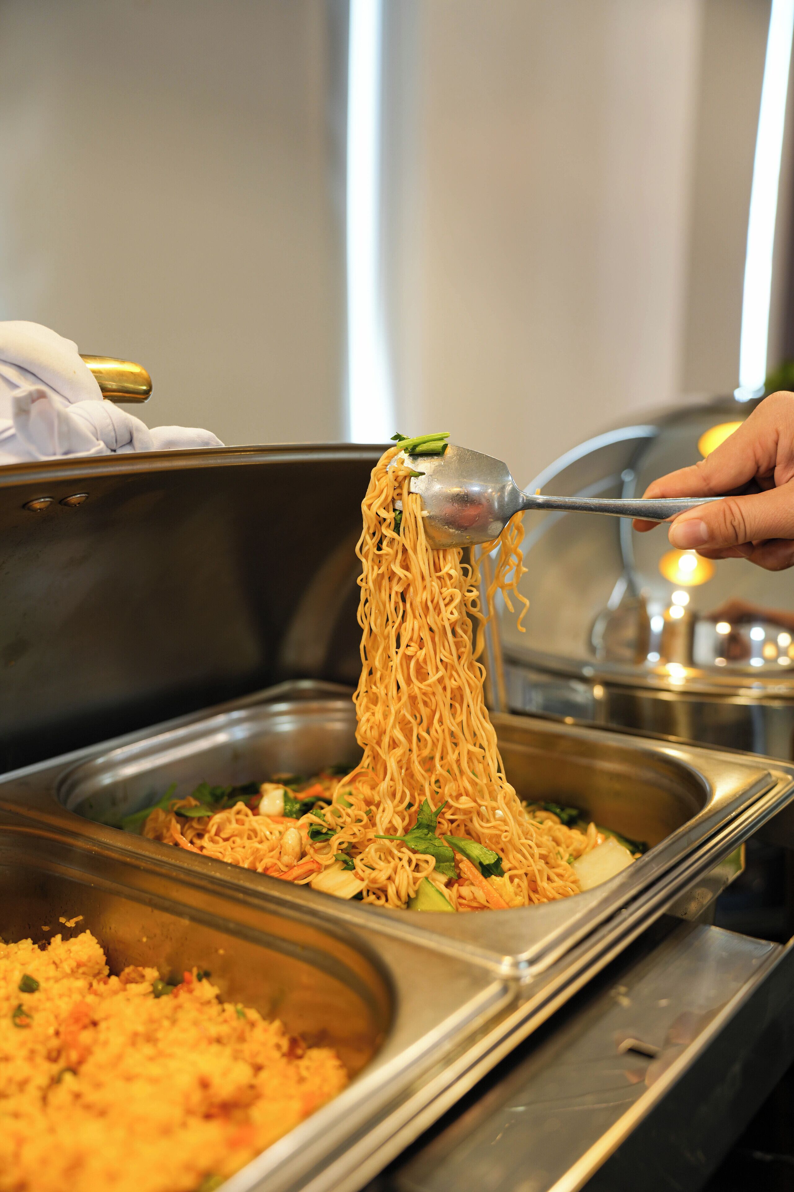 A buffet with various dishes, including noodles and a rice dish.