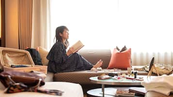 Une chambre d’hôtel avec un lit, un canapé, une petite table ronde et une valise.