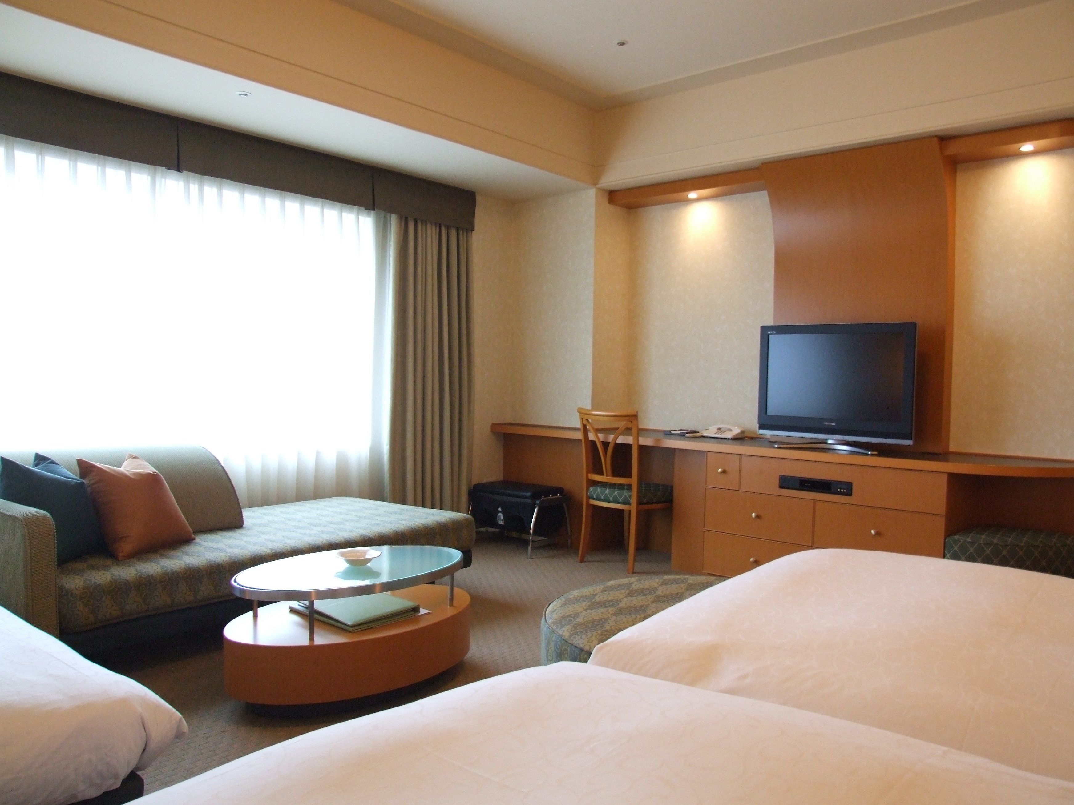A hotel room with a bed, a sofa, a TV, a desk, and a chair.