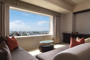 A modern hotel room with a large window offering a city view, a round coffee table, and a sofa with patterned cushions. - Urayasu Brighton Hotel Tokyo bay (Urayasu)