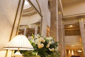 Um hall de entrada com uma luminária grande e um arranjo de flores.