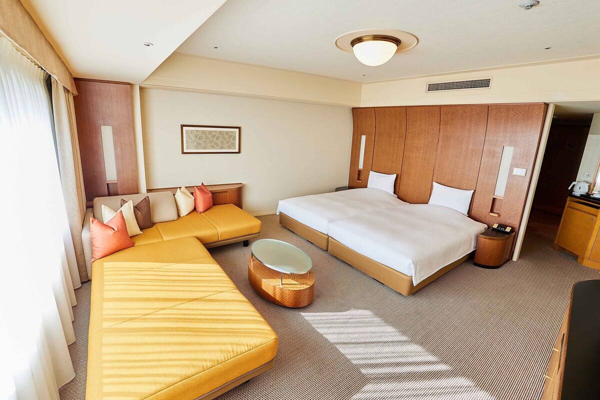 Una habitación de hotel con una cama grande, un sofá, una mesita y un espejo.