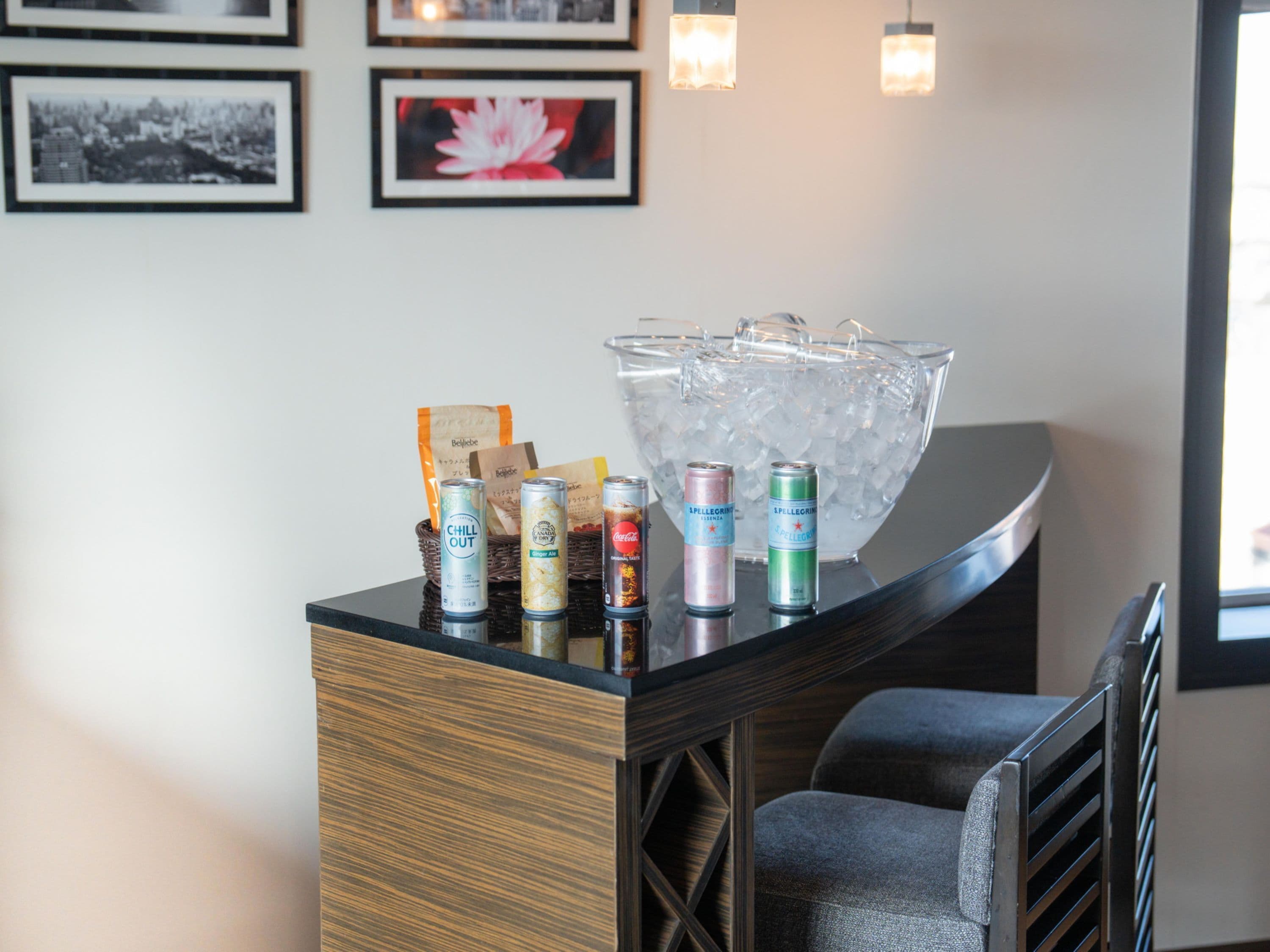 A reception desk with a beverage dispenser, a large ice-filled glass bowl, and a chair.