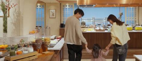 A modern kitchen with a buffet setup, featuring a variety of food items and a decorative plant.