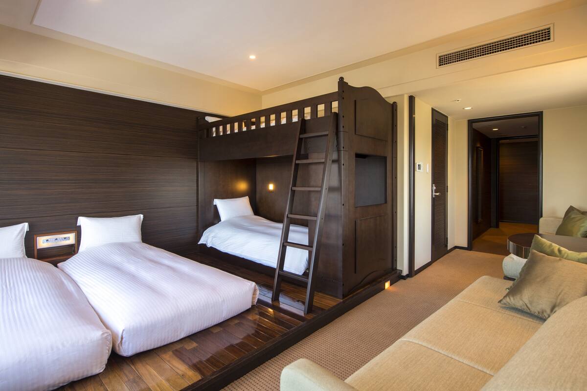 Habitación de hotel con dos camas, un sofá y una escalera.