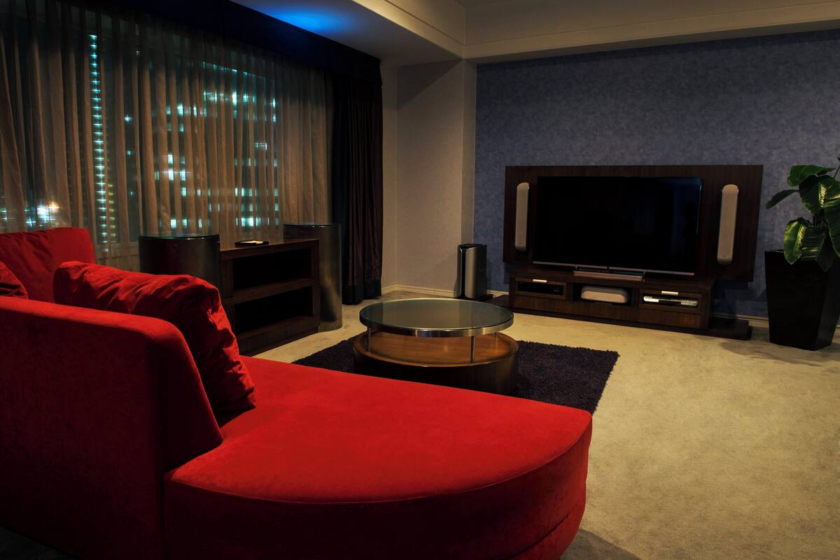 A modern living room with a red sofa, a glass coffee table, and a flat-screen TV on a wooden stand.