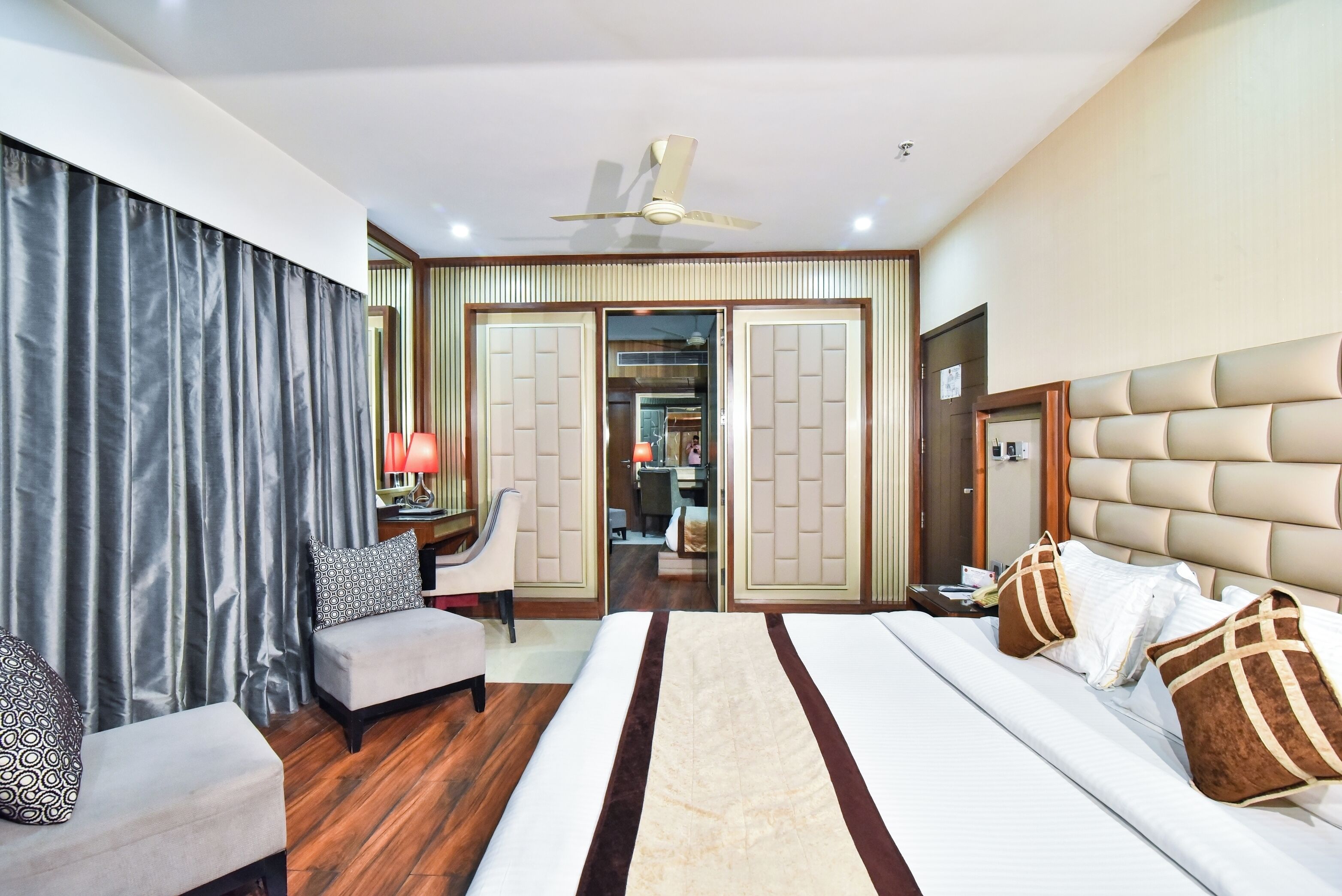 Una habitación de hotel con cama, escritorio, silla, armario y ventilador de techo.