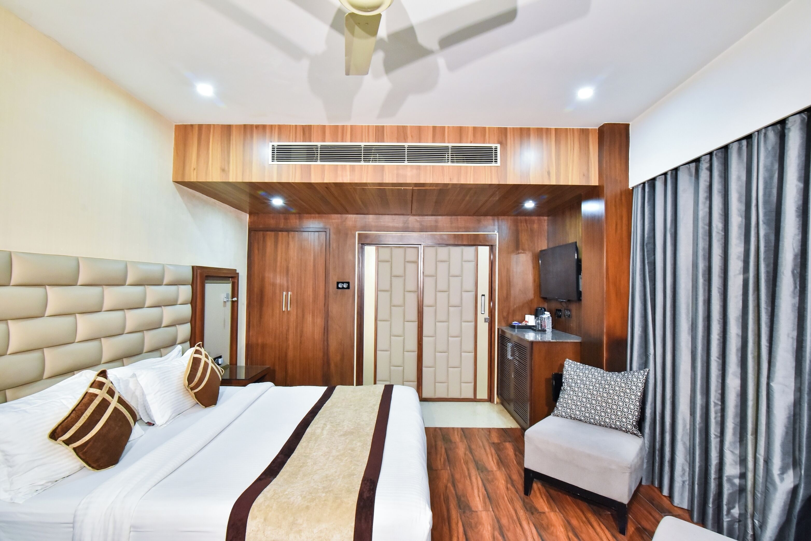 A hotel room with a large bed, a sofa, a TV, and a wardrobe.