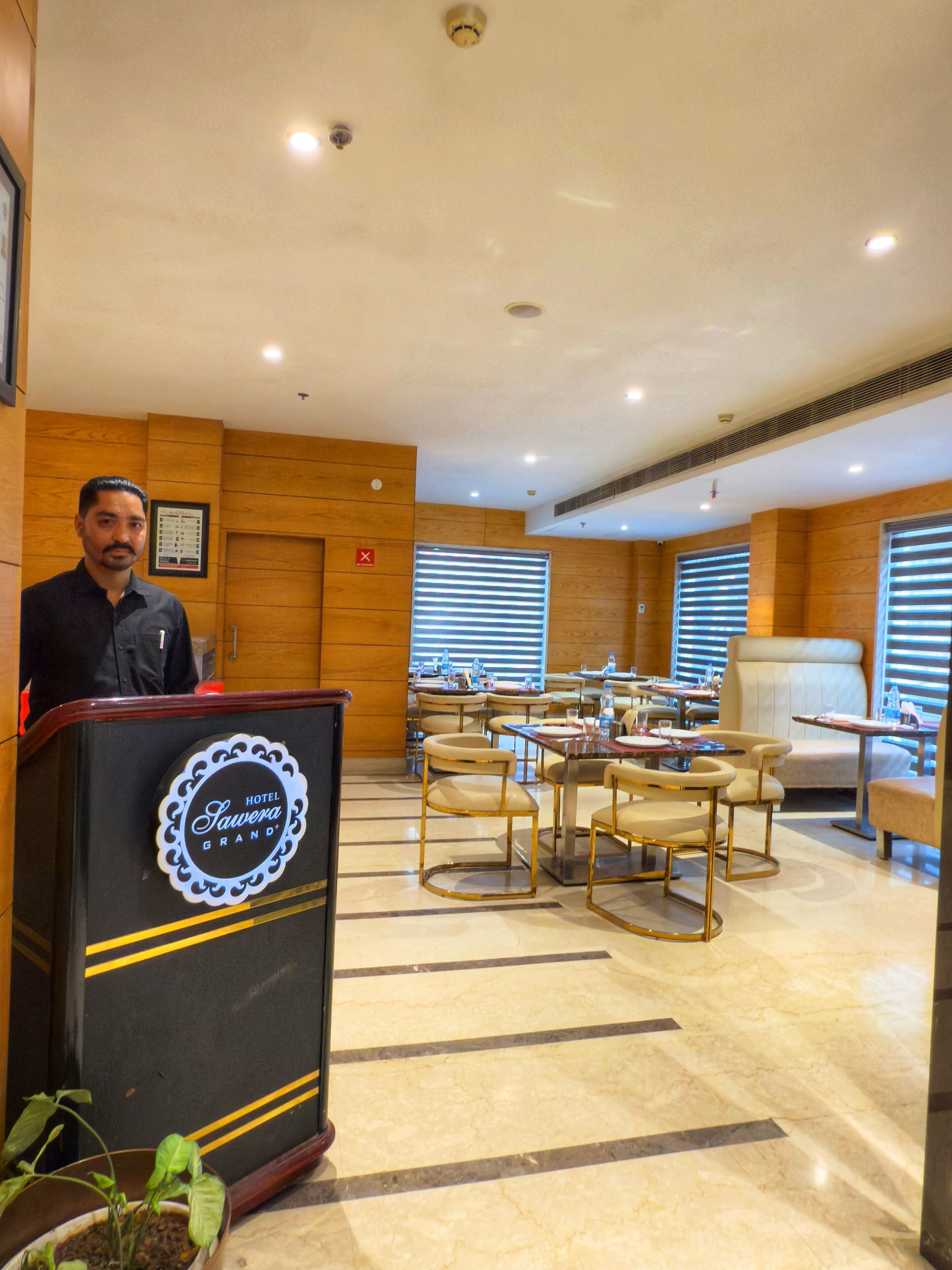 A hotel lobby with a podium, seating area, and a large window with blinds.