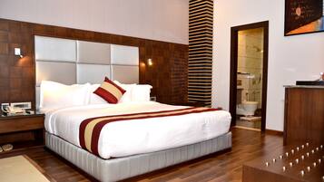 A modern hotel room with a large bed, wooden headboard, and a small desk with a telephone.