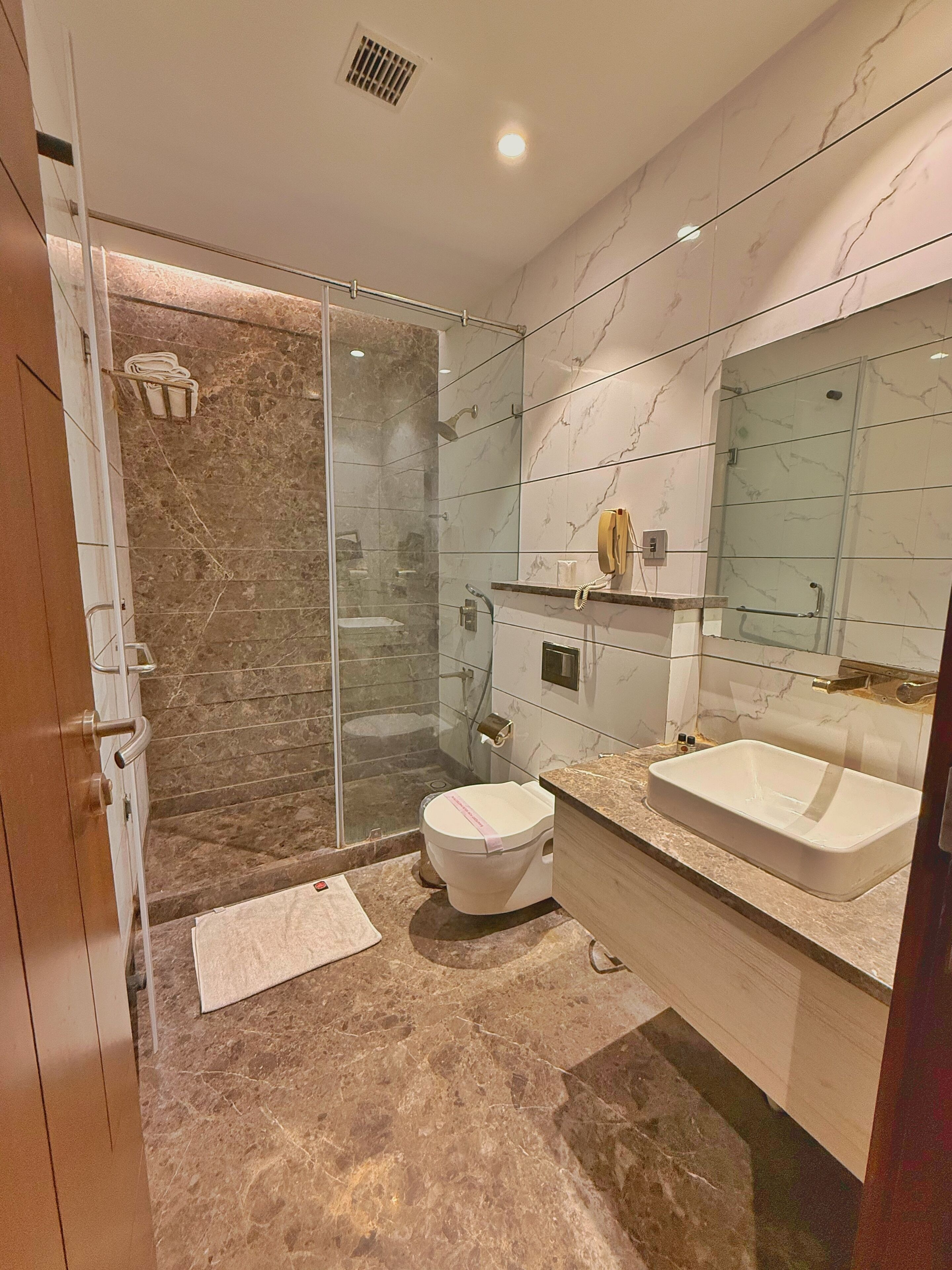 Un baño moderno con ducha de vidrio, inodoro, lavamanos y tocador.