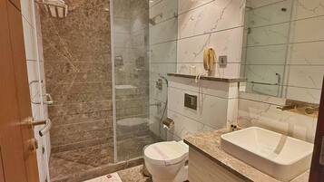 Un baño moderno con ducha de vidrio, inodoro, lavamanos y tocador.