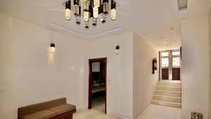 A spacious hallway with a modern chandelier, a sofa, and a staircase leading to another room.