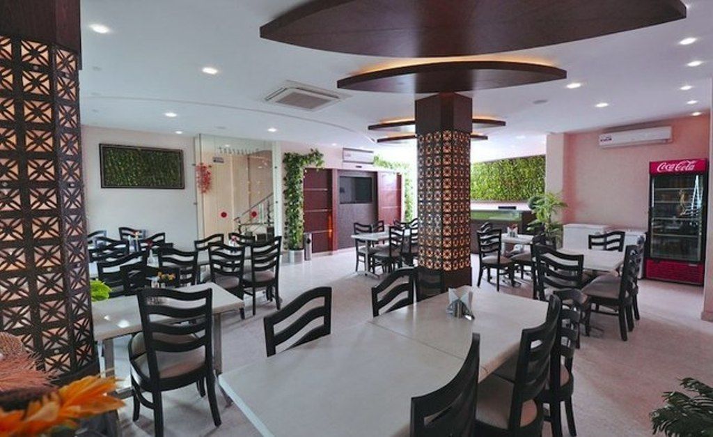 A restaurant with multiple tables and chairs, a decorative pillar, and a Coca-Cola refrigerator.