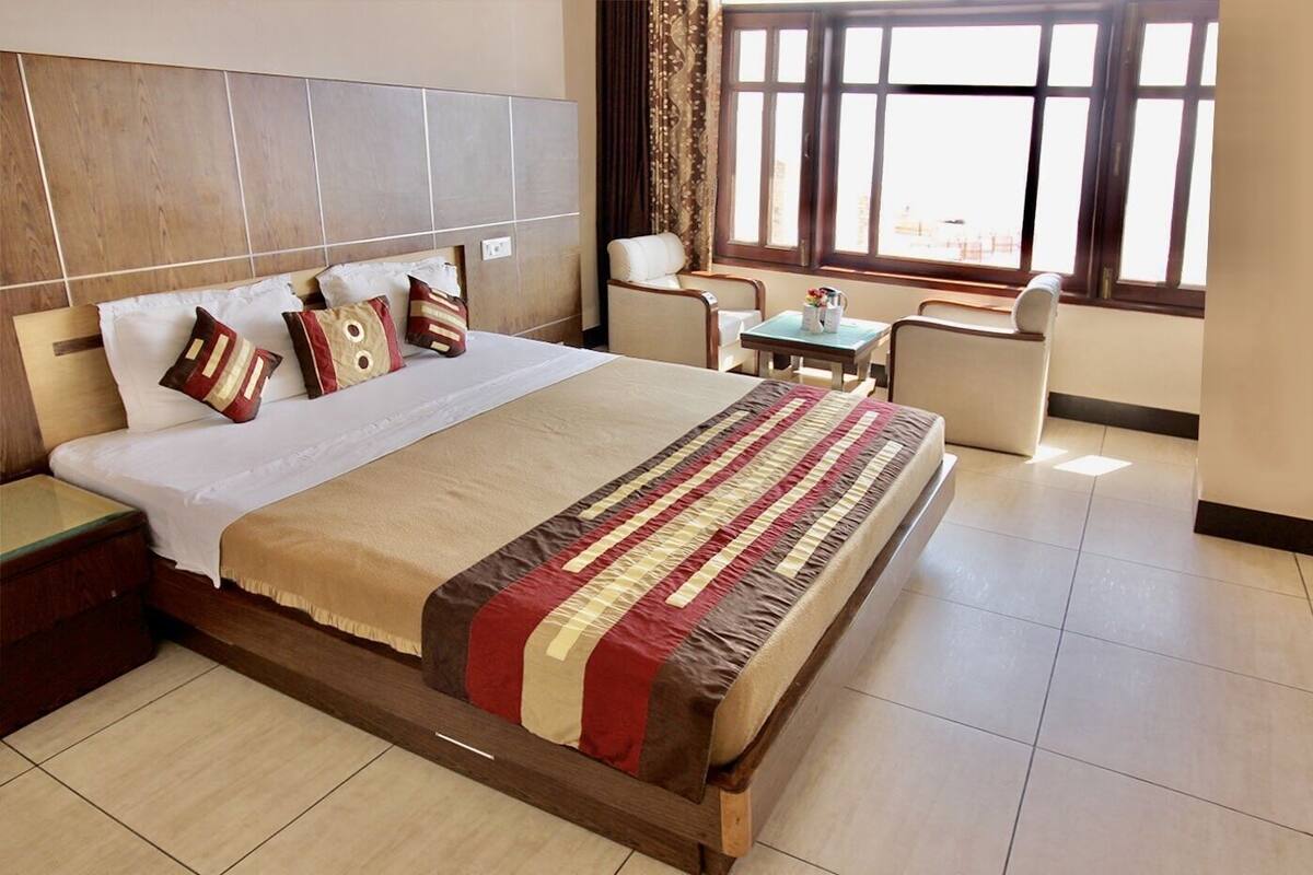 Una habitación de hotel con una cama grande, una mesita pequeña, una silla y una ventana con vistas.