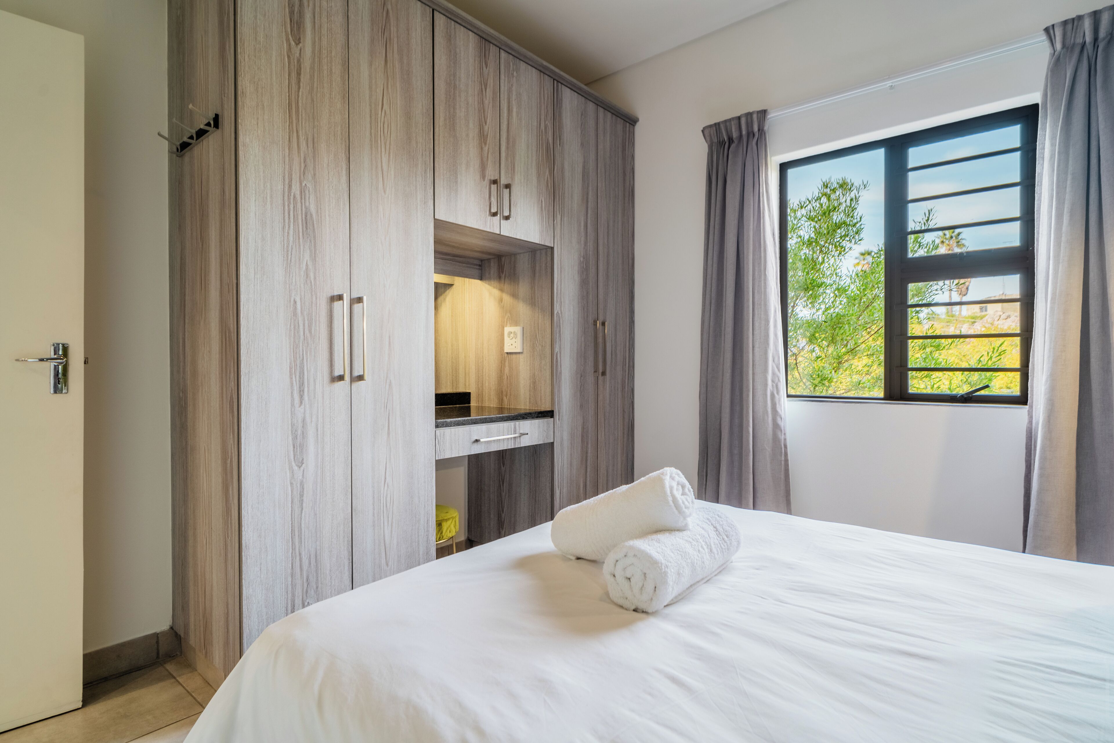 Quarto com cama grande, armário de madeira e janela com cortinas.