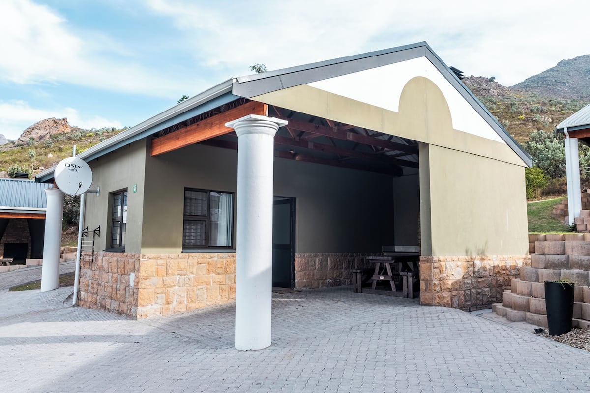 A building with a covered patio area, stone walls, and a satellite dish.