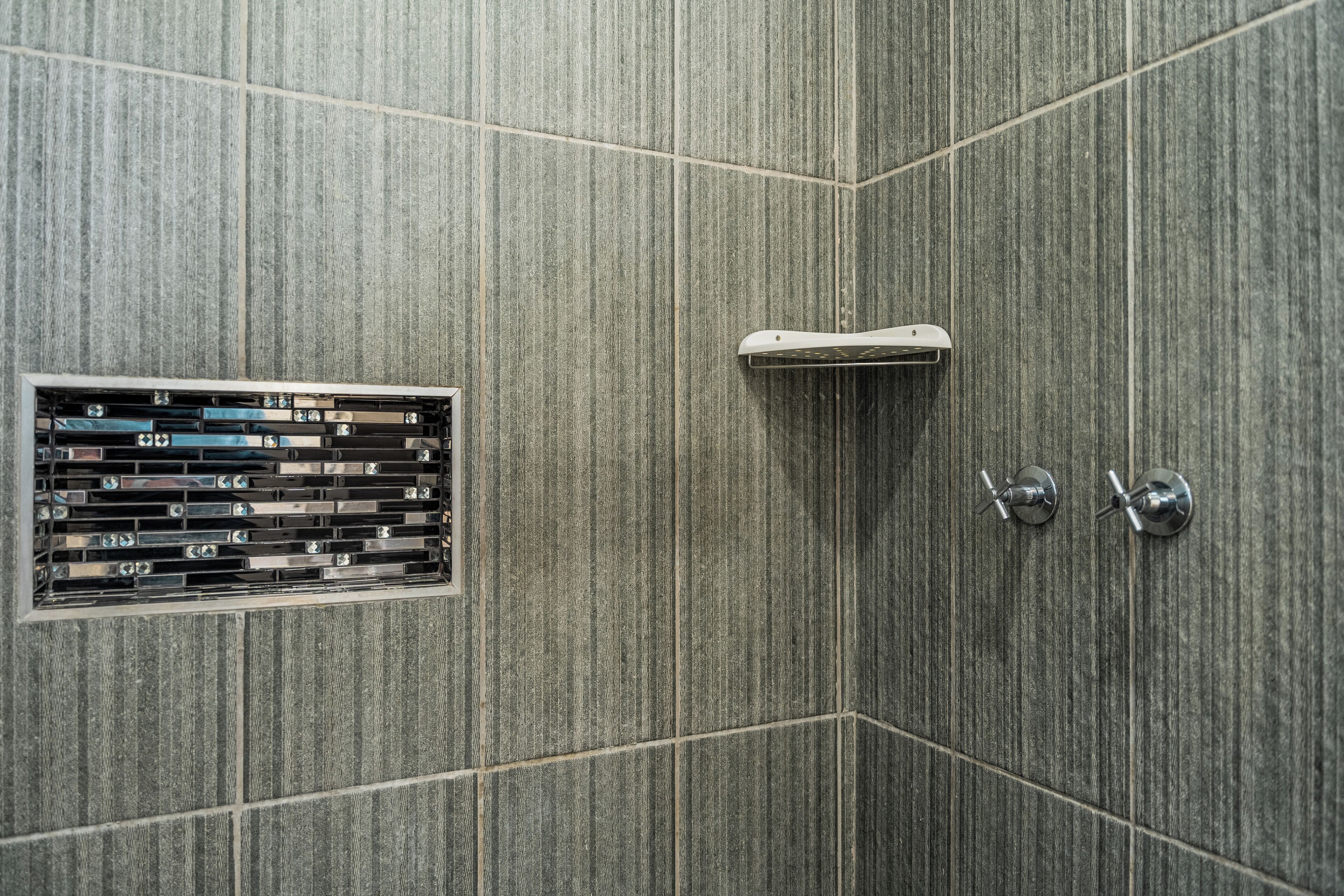 A shower area with a built-in control panel and a handheld showerhead.
