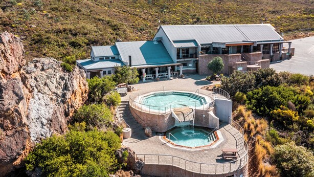 A resort with a pool, a building with a blue roof, and a mountainous backdrop. - ATKV Goudini Spa (Rawsonville)
