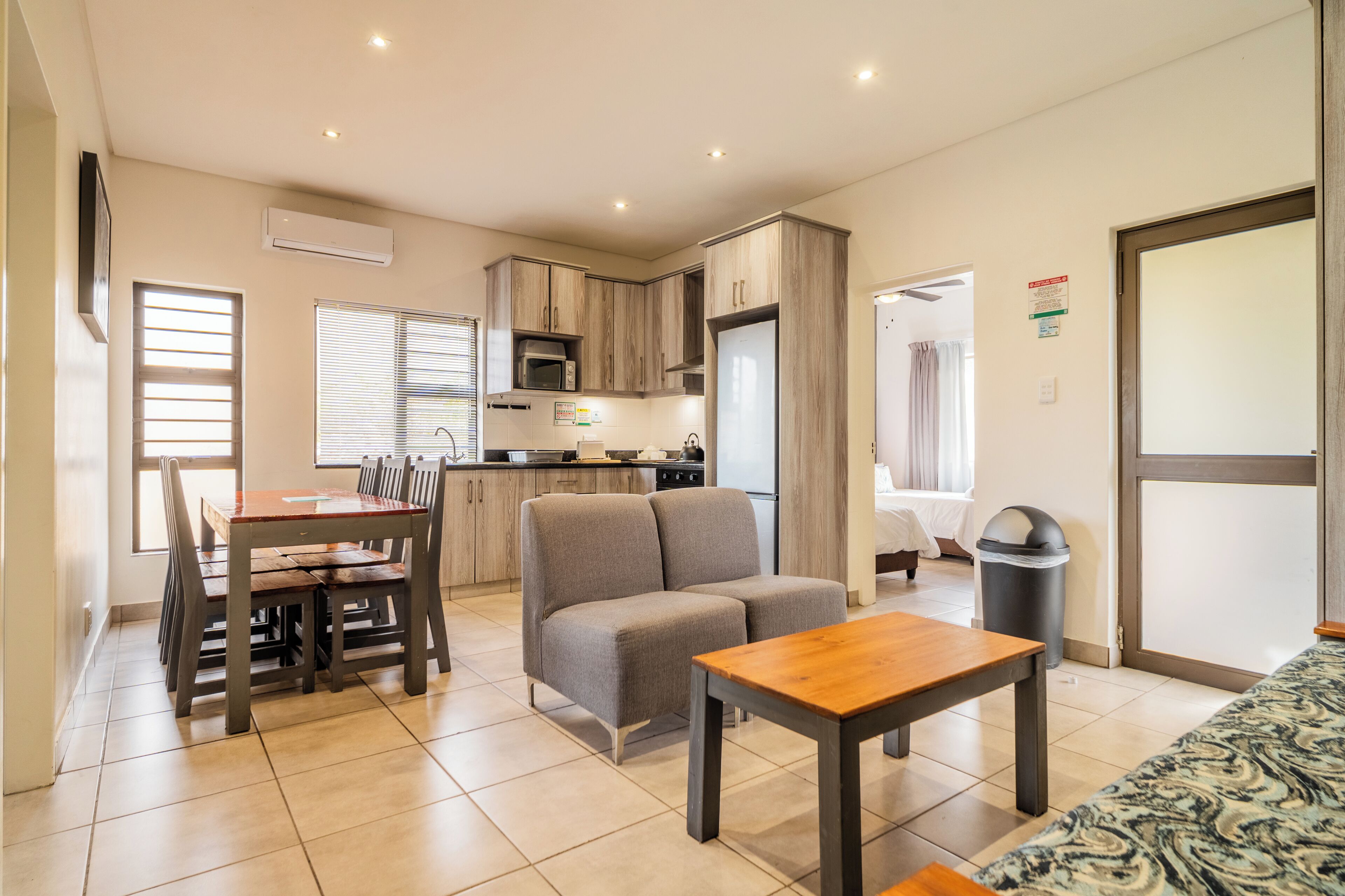 A modern apartment with a dining area, kitchenette, and a living room with a sofa and a table.