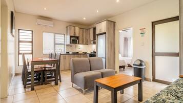 A modern apartment with a dining area, kitchenette, and a living room with a sofa and a table.