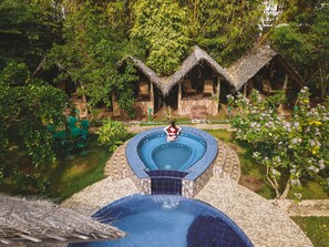 A circular pool with a tiled edge, surrounded by a stone pathway and lush greenery. - Sundaras Resort & Spa (Dambulla)