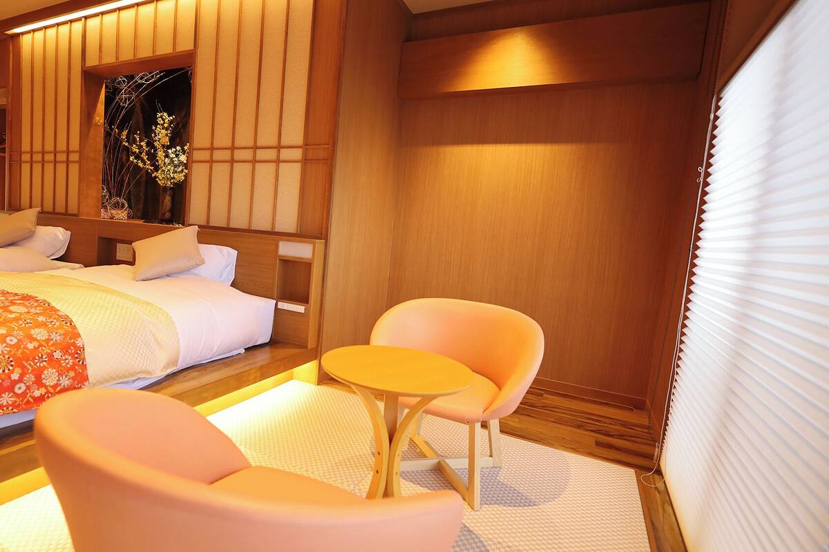 A hotel room with a bed, two chairs, a small table, and a decorative vase.