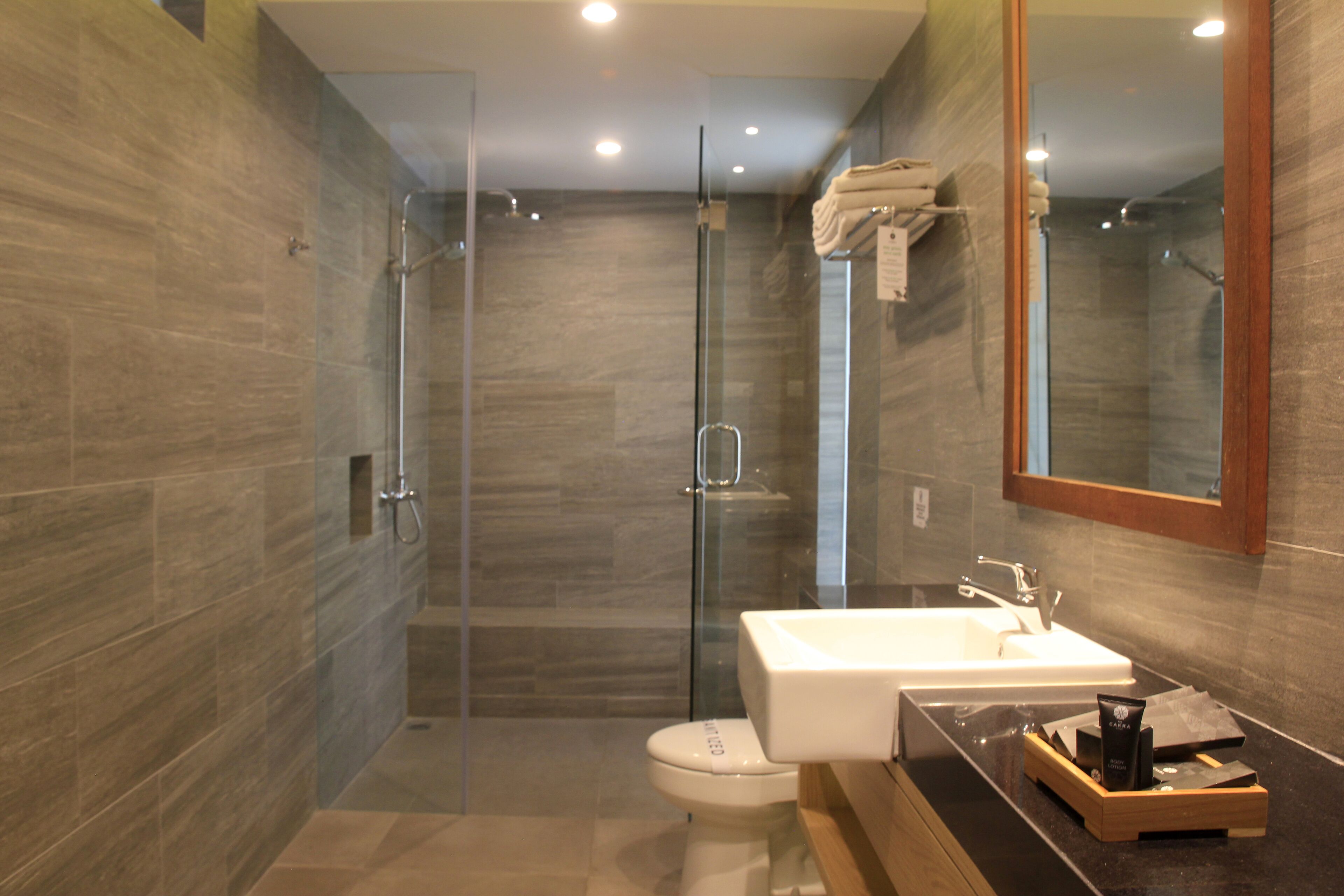 A modern bathroom with a glass-enclosed shower, a white sink, and a wooden vanity.