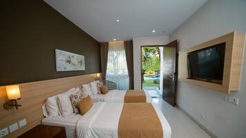 Habitación de hotel con dos camas, un televisor en la pared y vista al jardín por la ventana.