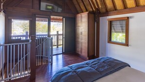 Een slaapkamer met een bed, een plafondventilator, een raam en uitzicht op de omgeving.