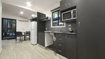 A modern kitchen with grey cabinets, a microwave, and a sink. There is a dining area with a table and chairs.