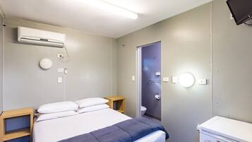 Ein Hotelzimmer mit Bett, Nachttisch, Schrank, Toilette und Fernseher.