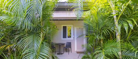 A house with a patio area, surrounded by lush greenery.