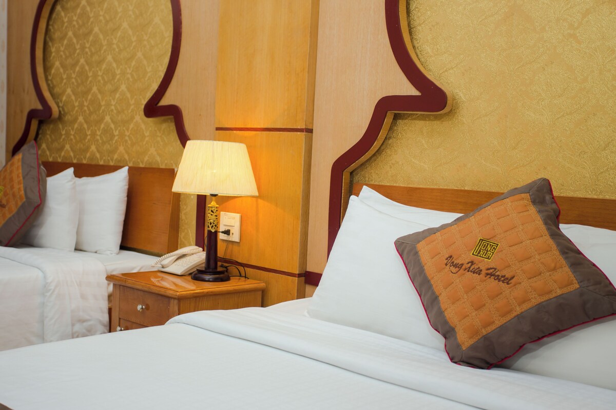 Une chambre d’hôtel avec un lit, une table de chevet avec une lampe et un téléphone.