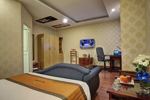 Ein Hotelzimmer mit Bett, Schreibtisch mit Computer, Fernseher und Kleiderschrank.