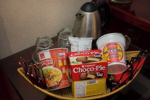Ein Korb mit verschiedenen Lebensmitteln, darunter Choco-Pie und Produkte der Marke Modern, eine Kaffeekanne sowie einige Gewürze.