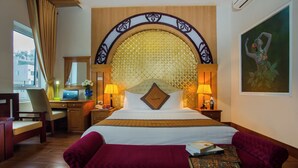 Une chambre d’hôtel avec un grand lit, un bureau, une chaise et un téléviseur.