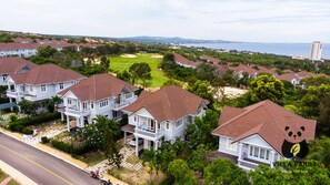 A residential area with houses featuring red-tiled roofs and white exteriors, surrounded by greenery and a golf course.